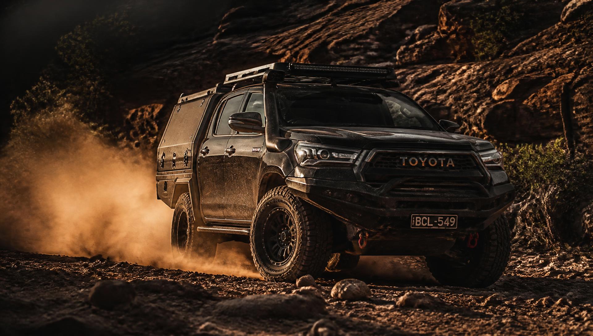 Lifted 4x4 pickup throwing dust on a rocky trail